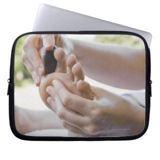 Woman getting foot massage with hot stone laptop sleeve